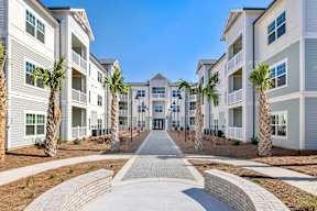 A row of white apartment buildings with a pathway in the middle.