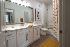 a bathroom with white cabinets and a white toilet next to a bathtub with a shower curtain