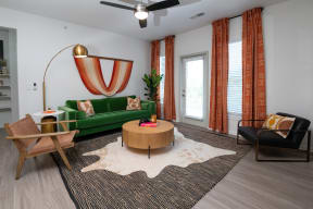 a living room with a green couch and orange curtains