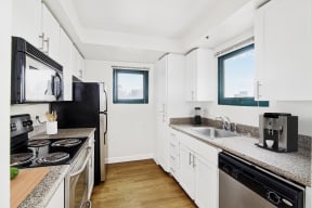 a kitchen with granite counter tops and black appliances and white cabinets