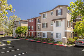 A parking lot in front of a multi-story apartment building.