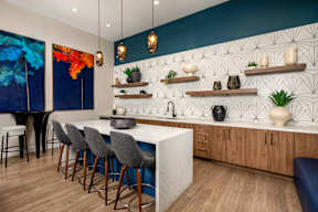 A kitchen with a white counter and bar stools.