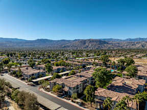 A suburban neighborhood with houses and palm trees under a clear blue sky.