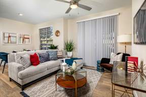 A living room with a grey couch, a coffee table, and a ceiling fan.