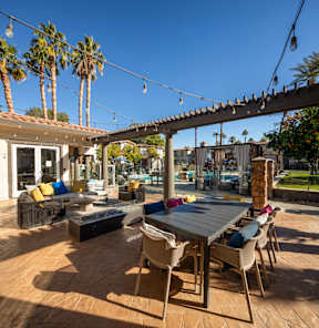 A patio with a table and chairs under a pergola with string lights.