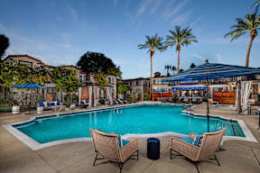 Two chairs are placed on the ground near a swimming pool.