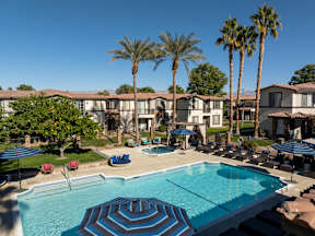 A swimming pool surrounded by palm trees and lounge chairs.
