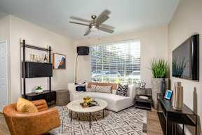 A living room with a white couch, a yellow chair, and a black television.
