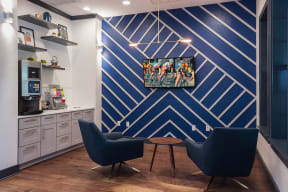 a room with two blue chairs and a coffee table with a tv on the wall