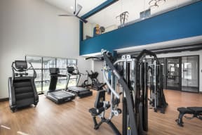 a gym with cardio equipment and weights on a wooden floor