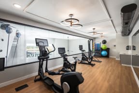 a gym with treadmills and other exercise equipment on a wood floor