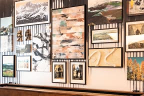 a wall of pictures on display in a gallery with a bench