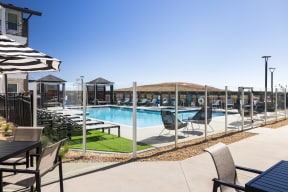 a pool with lounge chairs and tables at a resort