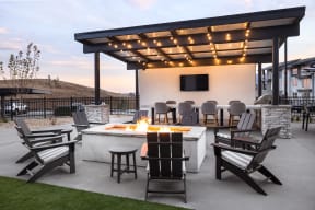 a patio with a fire pit and chairs and a tv