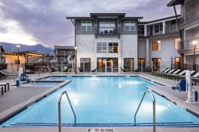 a swimming pool in front of an apartment building at dusk