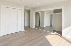 A room with white doors and wooden flooring.
