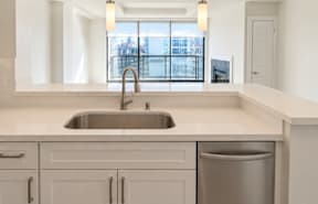 A modern kitchen with a stainless steel sink and white cabinets.