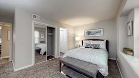 A bedroom with a bed, nightstand, and a mirror.