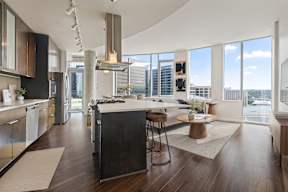 A modern kitchen with dark wood floors and stainless steel appliances.