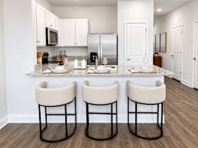 A kitchen with a bar and two stools.