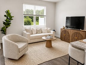 A living room with a white couch, a wooden cabinet, and a television.