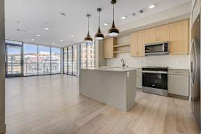 A modern kitchen with wooden floors and stainless steel appliances.
