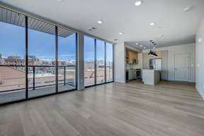 A spacious room with wooden floors and large windows overlooking a cityscape.