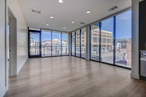 A spacious room with wooden floors and large windows overlooking a cityscape.