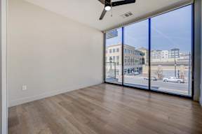 A room with a ceiling fan and a view of the street outside.