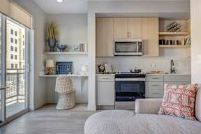 A modern kitchen with a white countertop and a grey couch.