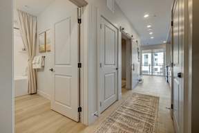 A hallway with a rug and a door on the left.