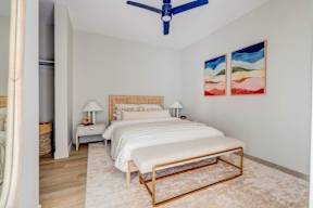 A bedroom with a bed, nightstands, and a ceiling fan.