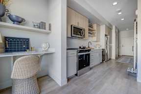 A kitchen with a white desk and a chair.