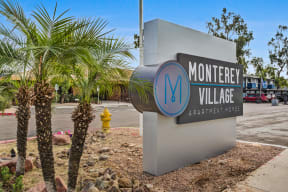 a sign for monterey village with a yellow fire hydrant in the background