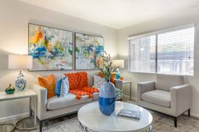 A living room with a white couch, a blue vase, and two paintings on the wall.