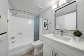A white bathroom with a toilet, sink, and shower.