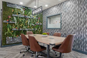 A conference room with a green plant wall and a wooden table Avondale apartments for rent at Newport.