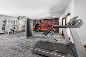 A treadmill in a gym with a red painting in the background.