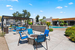 A poolside area with blue chairs and a table.