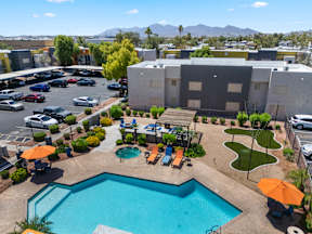 A swimming pool surrounded by a patio with chairs and umbrellas.