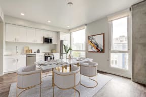 a dining area with a table and chairs and a kitchen in the background