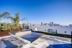 a rooftop terrace with a ping pong table and a view of the city
