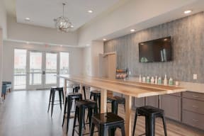 a bar with black stools in a room with a counter and a television