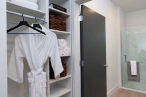 a closet with robes and towels and a shower