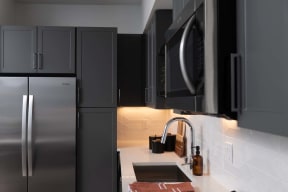 a kitchen with black cabinets and a sink and a refrigerator
