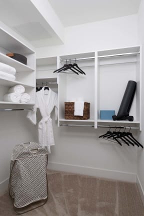 a walk in closet with white shelves and a robe and clothes rack