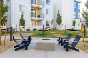 a patio with chairs and a fire pit in front of a building