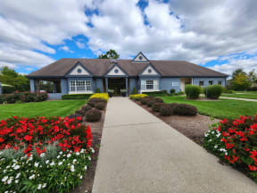 a house with a sidewalk in front of a yard with flowers
