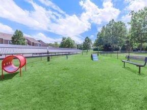 a dog park with a seesaw and benches in the grass