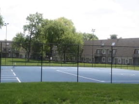 a tennis court in front of an apartment building